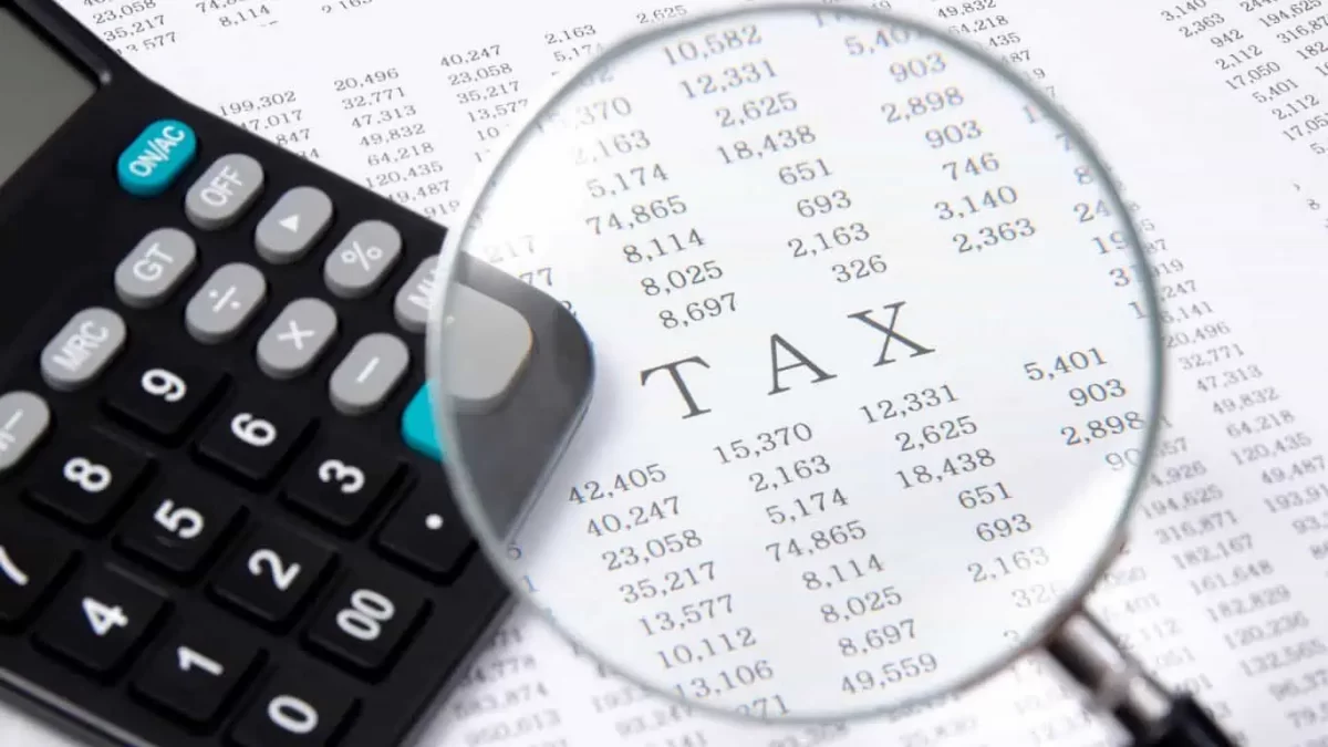 a calculator and a magnifying glass on a paper with word tax