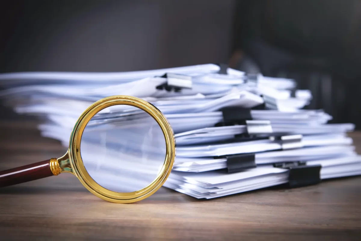 a magnifying glass on a table with a stack of contracts
